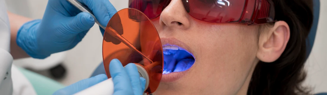 woman receiving teeth whitening treatment while wearing goggles