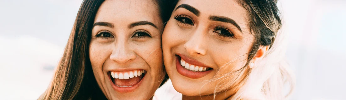 Dentist Orlando FL Veneers Focused two smiling women embracing showing off their veneers