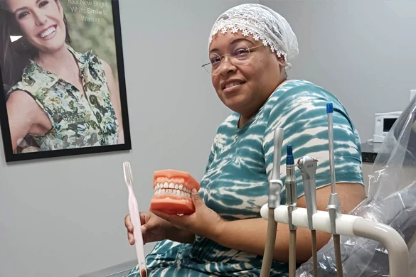 Dentist Orlando FL You Deserve A Beautiful Smile a patient is seen holding a model of teeth while displaying a toothbrush while smiling at the viewer